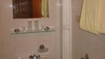 Un baño con lavamanos, espejo y toallero.