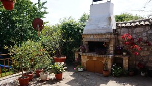 A stone patio with a brick oven and potted plants. - Margarita (Varna)