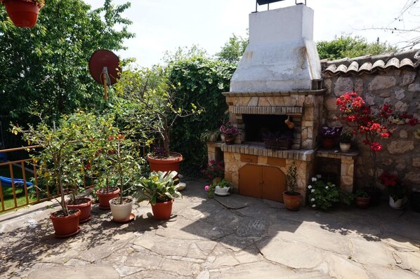 Un patio de piedra con un horno de ladrillo y plantas en macetas.