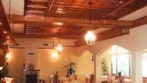 A wooden-floored dining area with a high ceiling and hanging light fixtures. - Margarita (Varna)