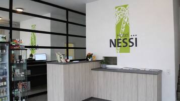 Una recepción de hotel con diseño moderno, un expositor de vidrio con servicios y un cartel en la pared para Hotel NESSI.