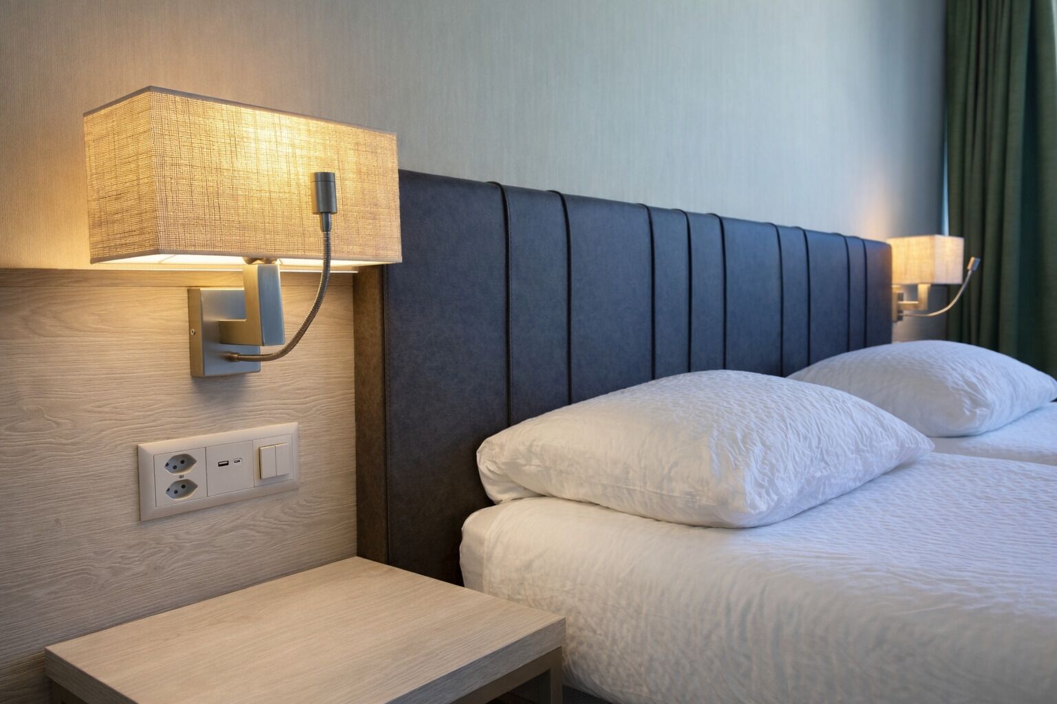 Une chambre d’hôtel comprenant un lit, deux lampes de chevet, une table de chevet et une prise de courant.