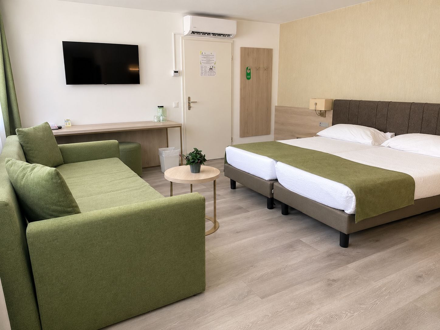 Een hotelkamer met een bed, een bank, een kleine tafel en een televisie.