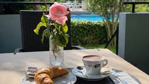 Ein Tisch mit einem Croissant, einer Tasse Kaffee und einer Vase mit einer rosa Rose.