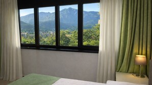 Ein Schlafzimmer mit einem Bett, einem Nachttisch mit Lampe und einem Fenster mit Vorhängen.
