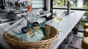 Eine Bar mit einem Korbwägelchen voller Snacks und einem Glas Weißwein.