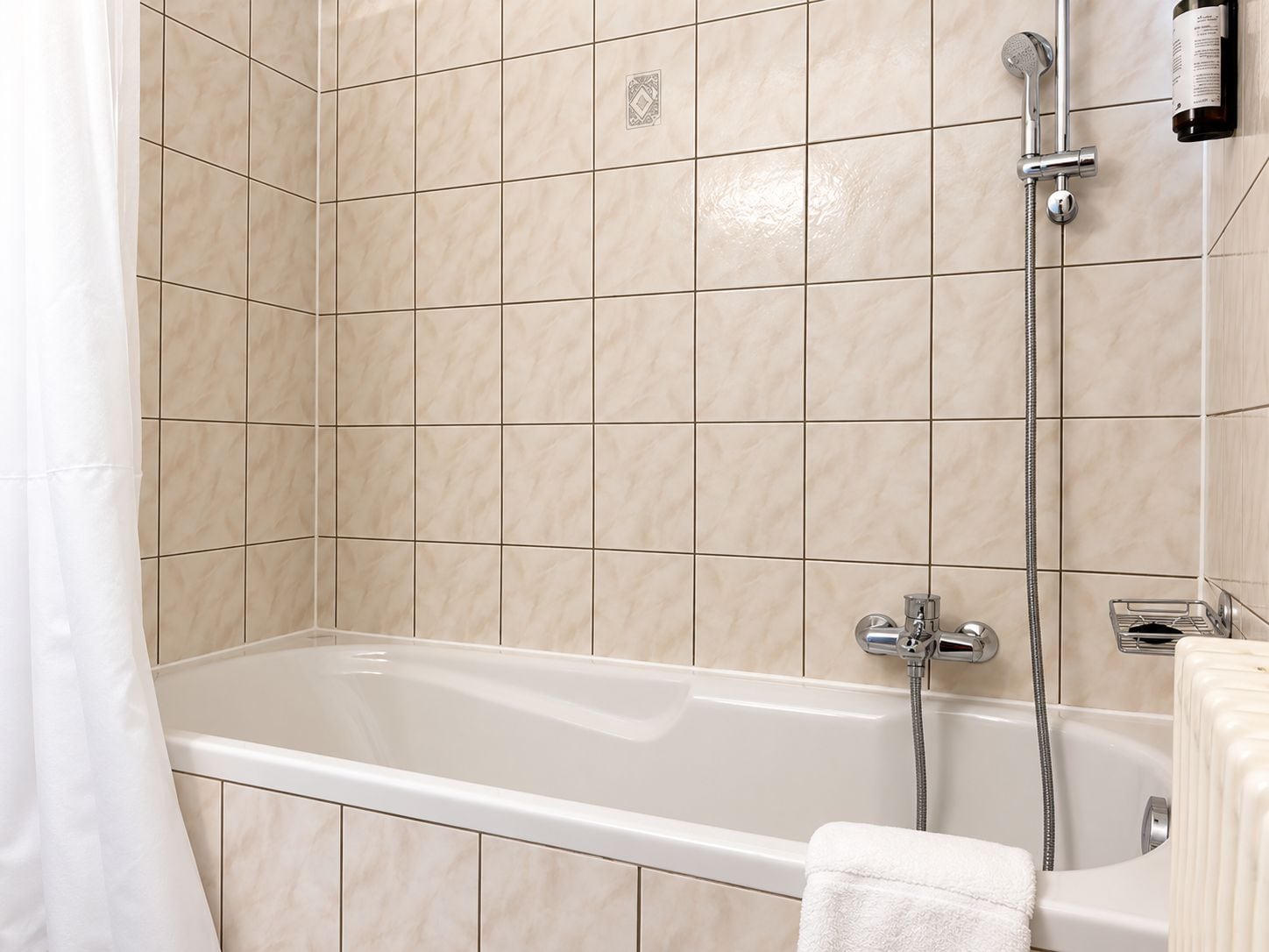 A bathroom with a bathtub, a showerhead, and a towel rack.
