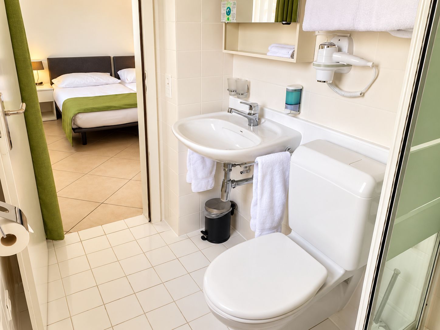 Une salle de bain d’hôtel équipée de toilettes, d’un lavabo et d’une zone douche.