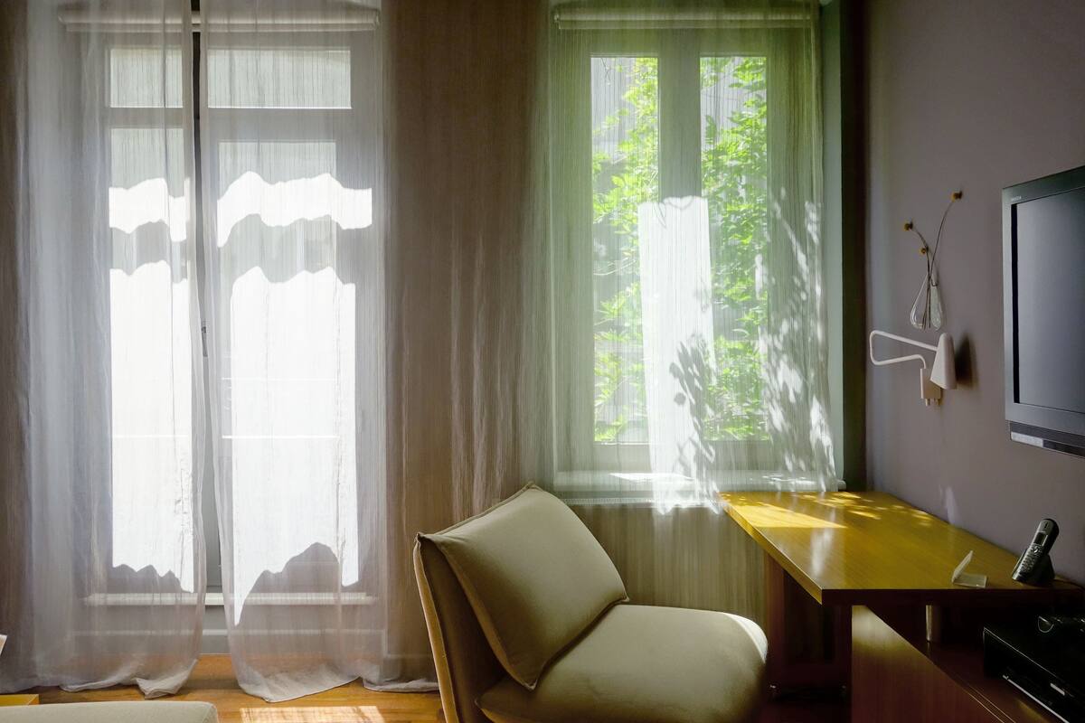 Una habitación con un escritorio de madera, una silla y un televisor en la pared.