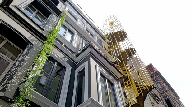 A building with a modern facade, large windows, and a yellow fire escape. - I'zaz (Istanbul)