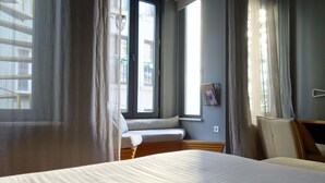 A hotel room with a bed, a bench by the window, and curtains. - I'zaz (Istanbul)
