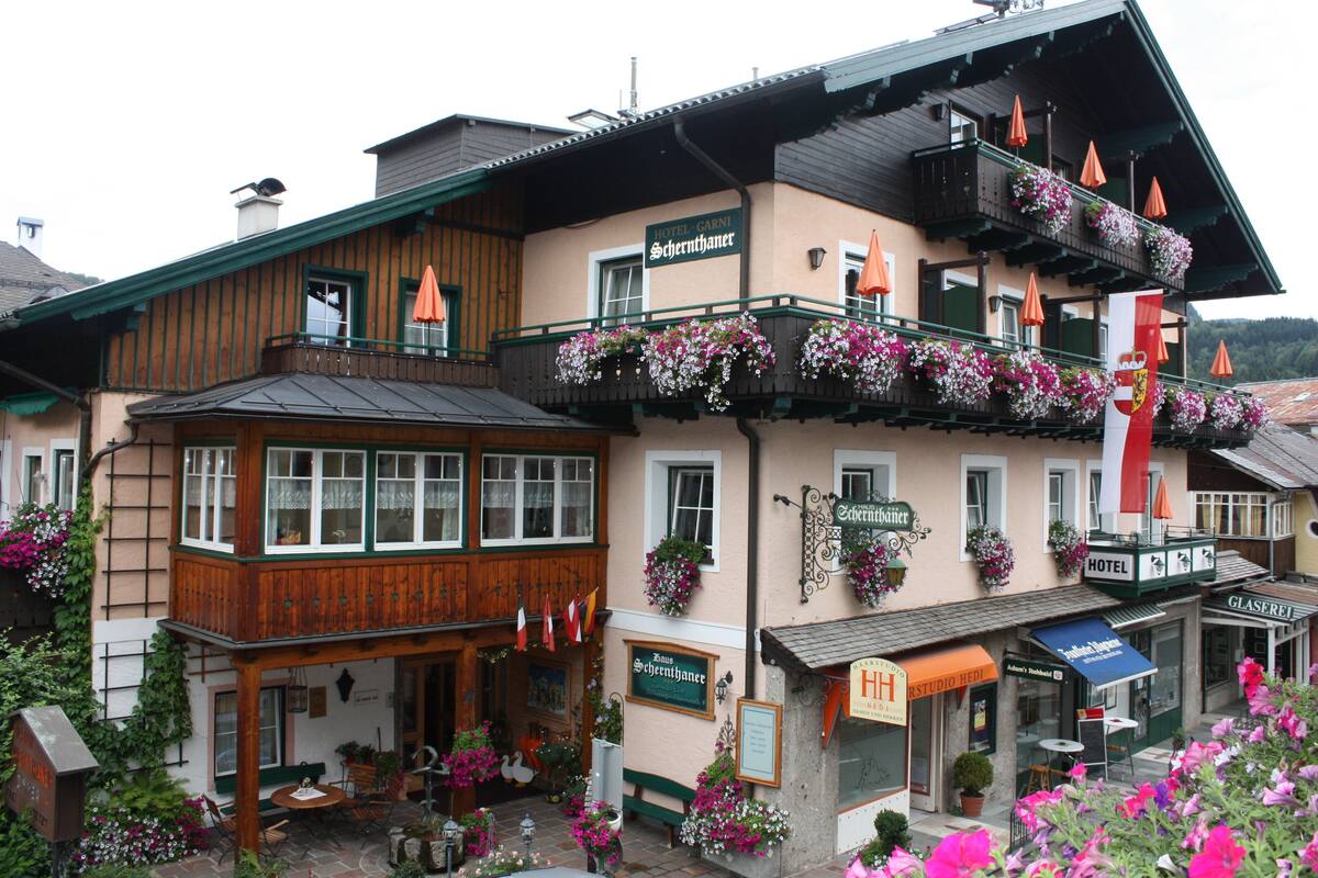 Ein Hotel mit Holzfassade, Balkonen mit Blumenkästen und einem Schild mit der Aufschrift 'Hotel Garni'.
