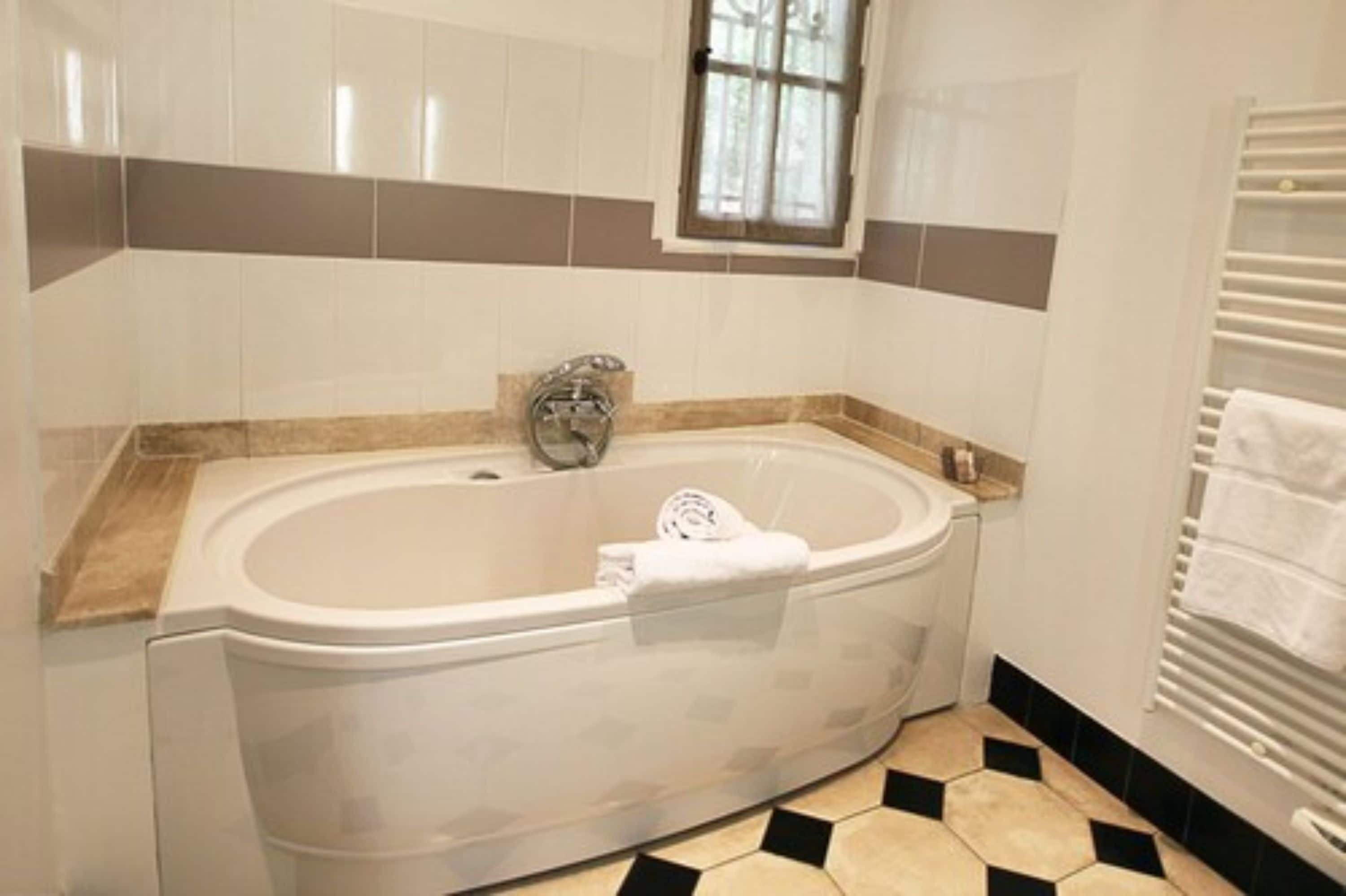 A bathroom with a freestanding bathtub, a window, and a towel rack.