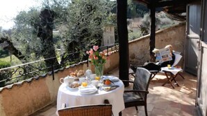A balcony with a table set for breakfast, surrounded by wicker chairs, and overlooking a scenic landscape. - Hotel du Clos (Le Rouret)