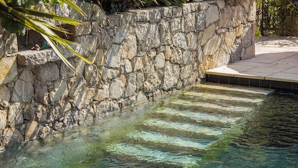 A stone wall with a clear pool. - Hotel du Clos (Le Rouret)