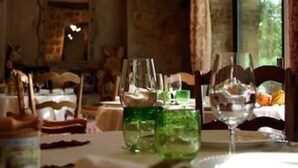 A rustic dining room with exposed brick walls, wooden beams, and a large window. - Hotel du Clos (Le Rouret)