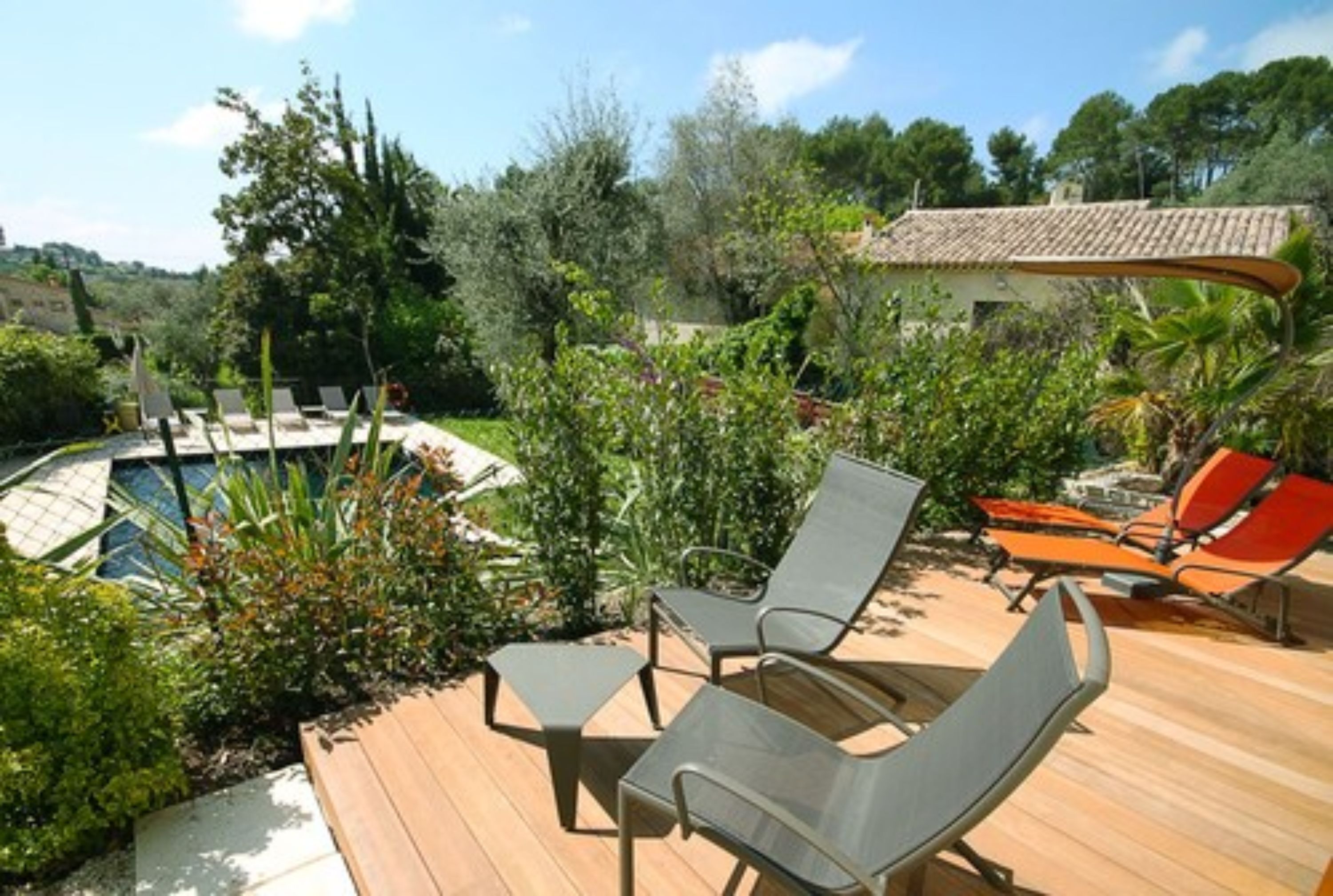 Una terraza de madera con sillones de descanso y una piscina.