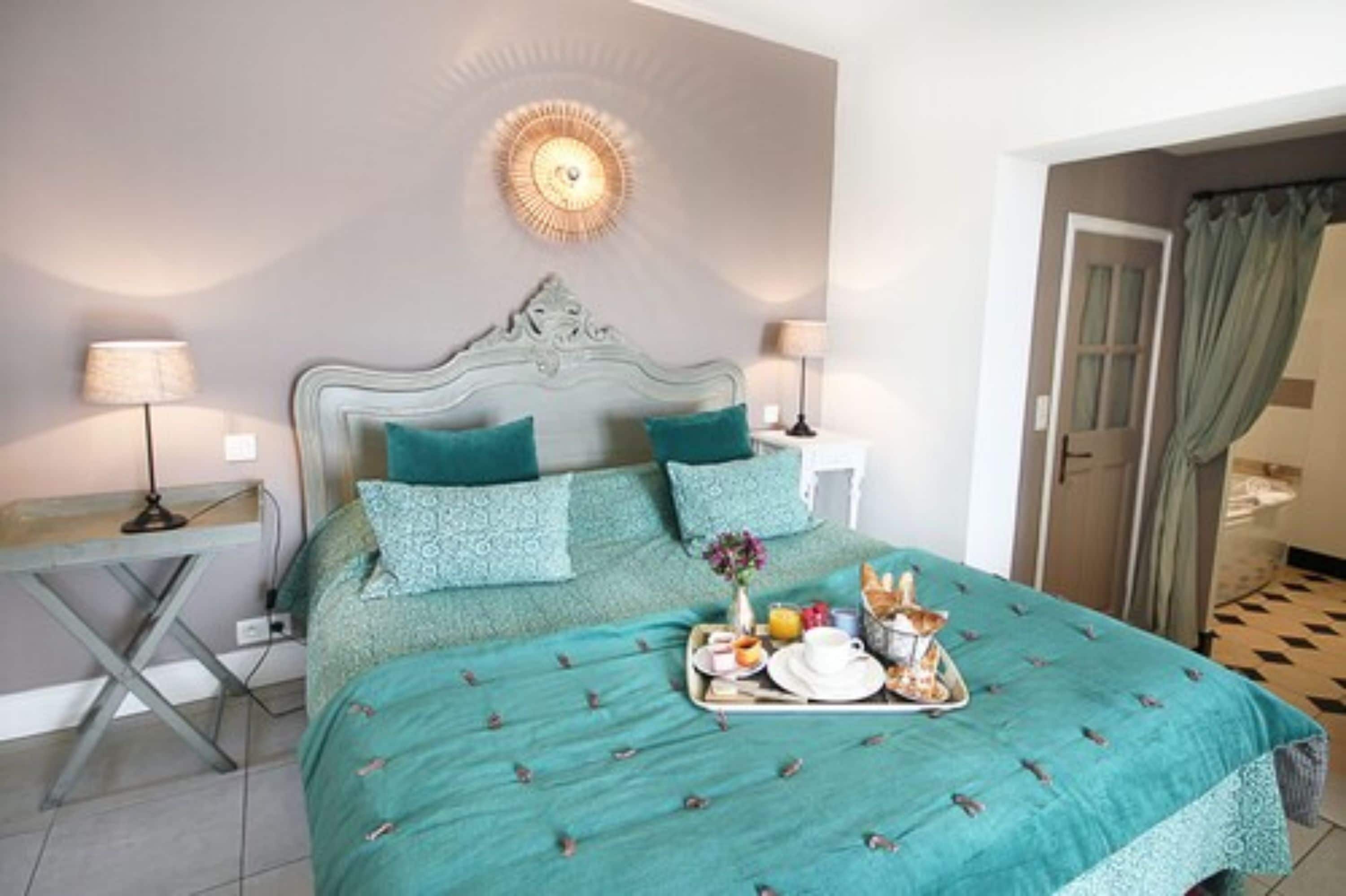 Une chambre à coucher avec un lit, des tables de chevet, une lampe fixée au mur et un plateau de petit-déjeuner posé sur le lit.