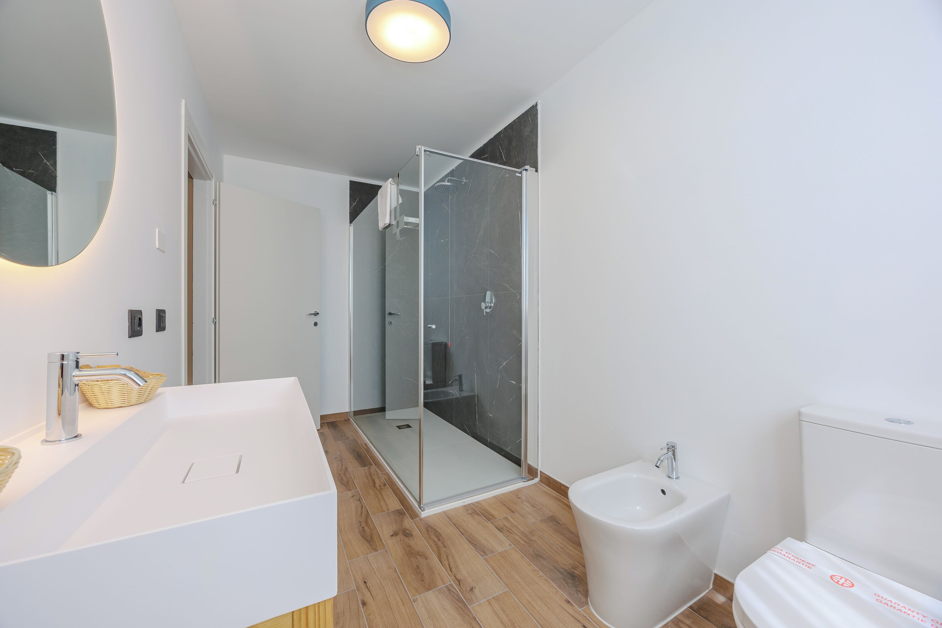 Un bagno moderno con un lavandino bianco, un bidet e una cabina doccia in vetro.