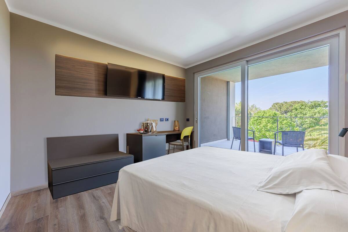 A modern hotel room with a large bed, a desk, and a seating area.