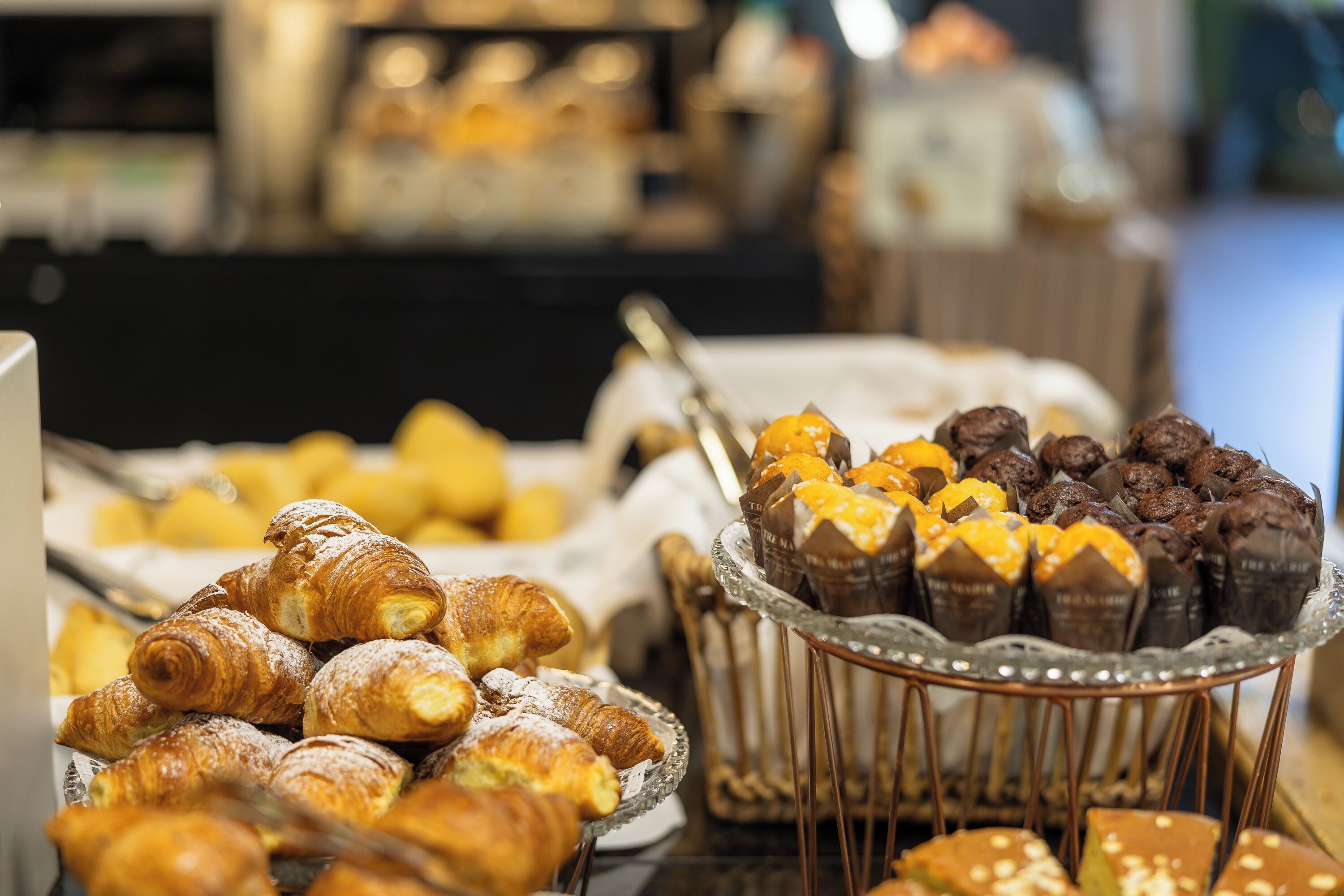A buffet with various pastries including croissants and chocolate-covered confections.