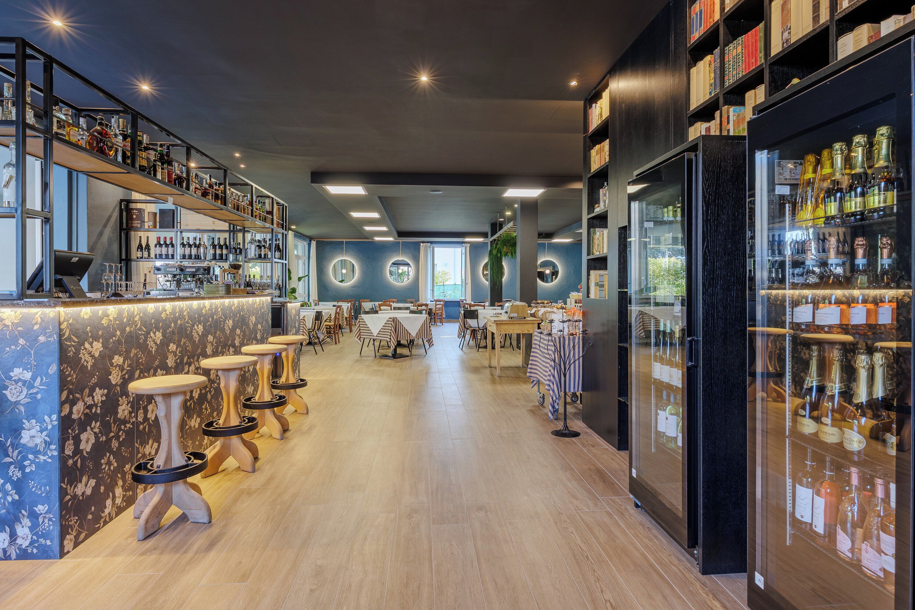 Un área de bar moderna con taburetes de madera, una barra y estantes llenos de botellas.