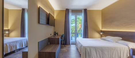 Una habitación de hotel moderna con una cama grande, un escritorio y un balcón con vistas a palmeras.
