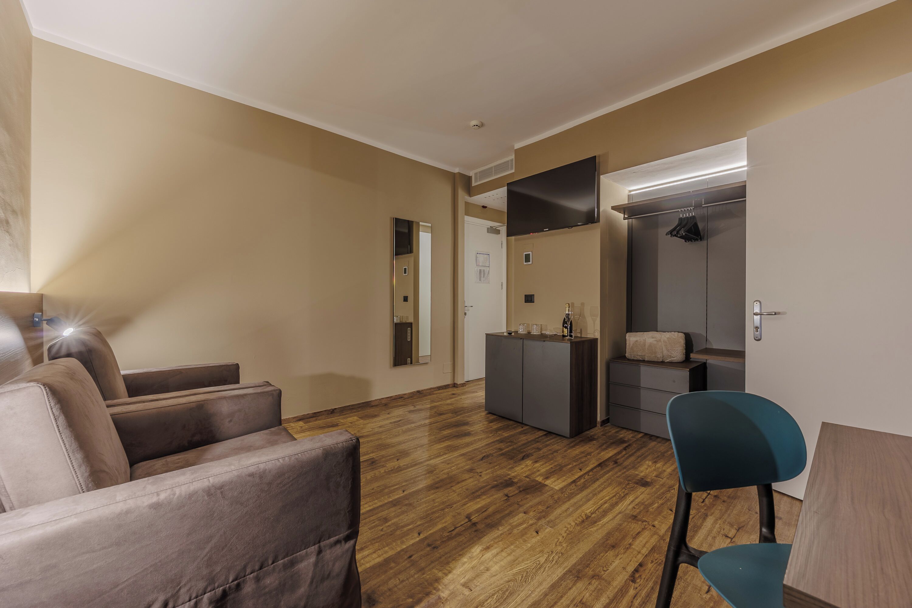 A modern living room with a sofa, a chair, a small table, a TV, and a wardrobe.