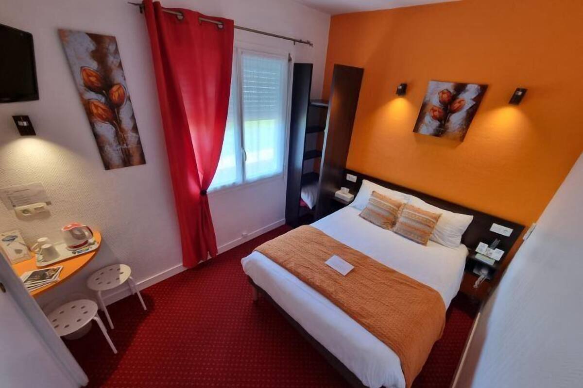 Habitación de hotel con cama, escritorio, silla y obras de arte en las paredes.