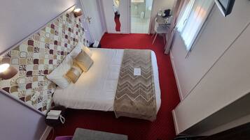 A hotel room with a bed, bedside table, lamp, and a view of the bathroom.