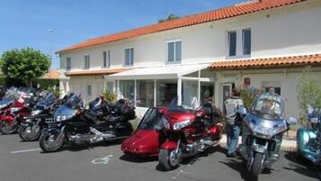 Una fila de motocicletas estacionadas frente a un edificio con techo de tejas y entrada cubierta.