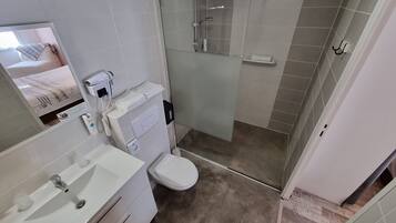 A bathroom with a toilet, sink, and shower area.