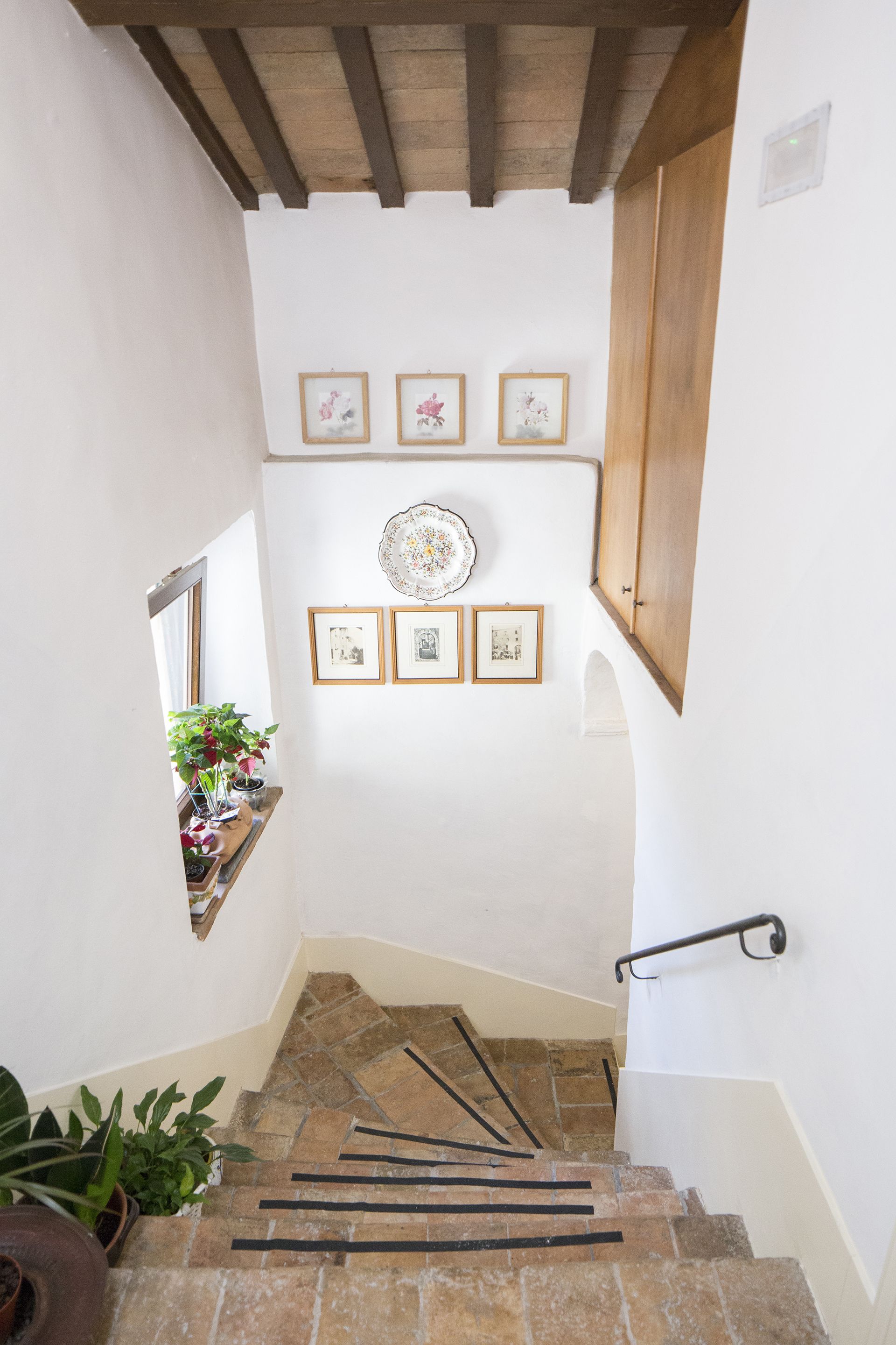 A staircase with stone steps, wooden handrails, and framed pictures on the walls.
