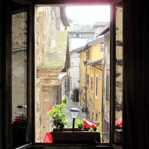 A narrow street view through an open window with a potted plant in the foreground. - Hotel Porta del Tempo (Stroncone)