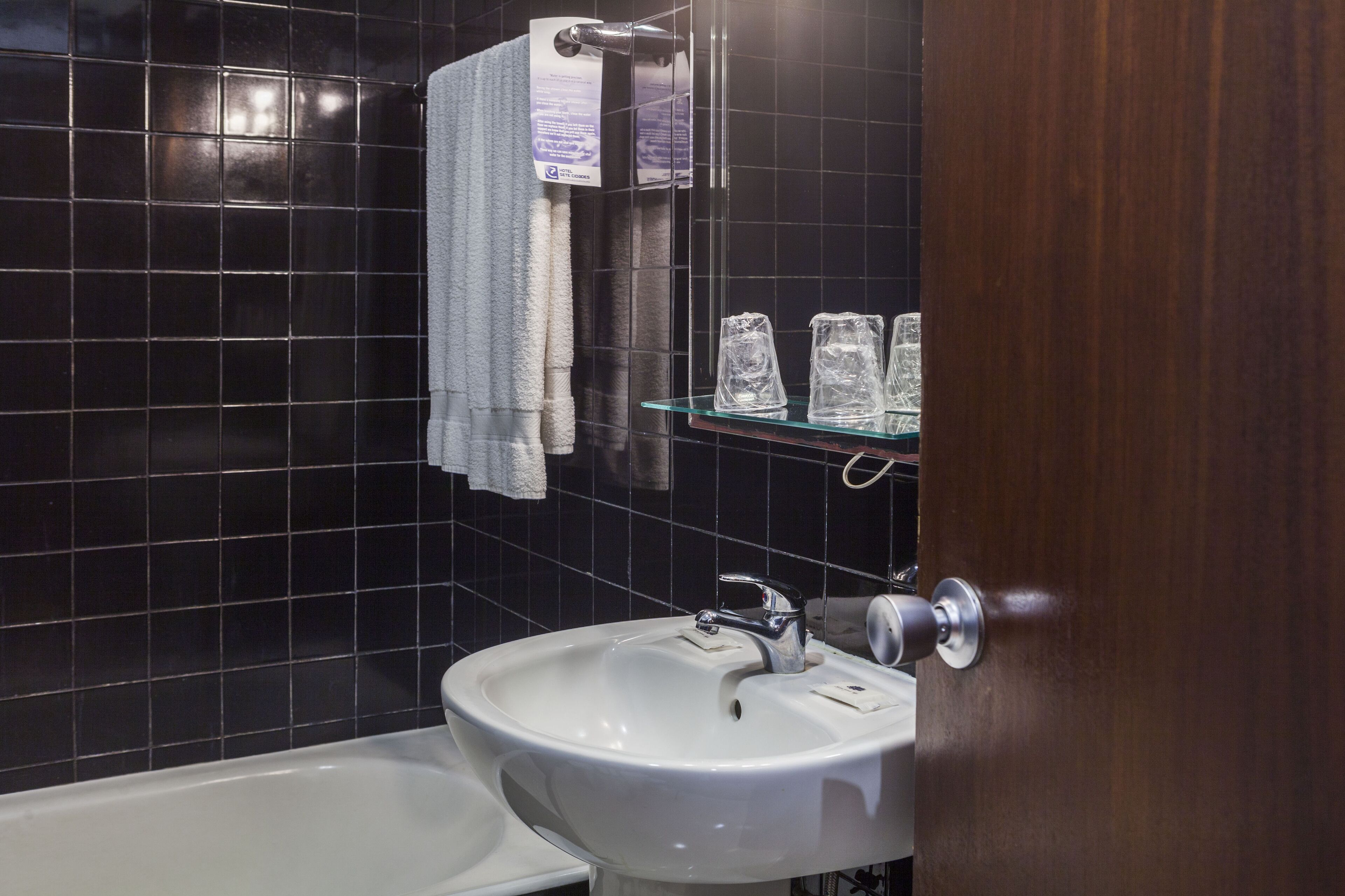 A bathroom with a white sink, a mirror, and a glass shelf with toiletries.