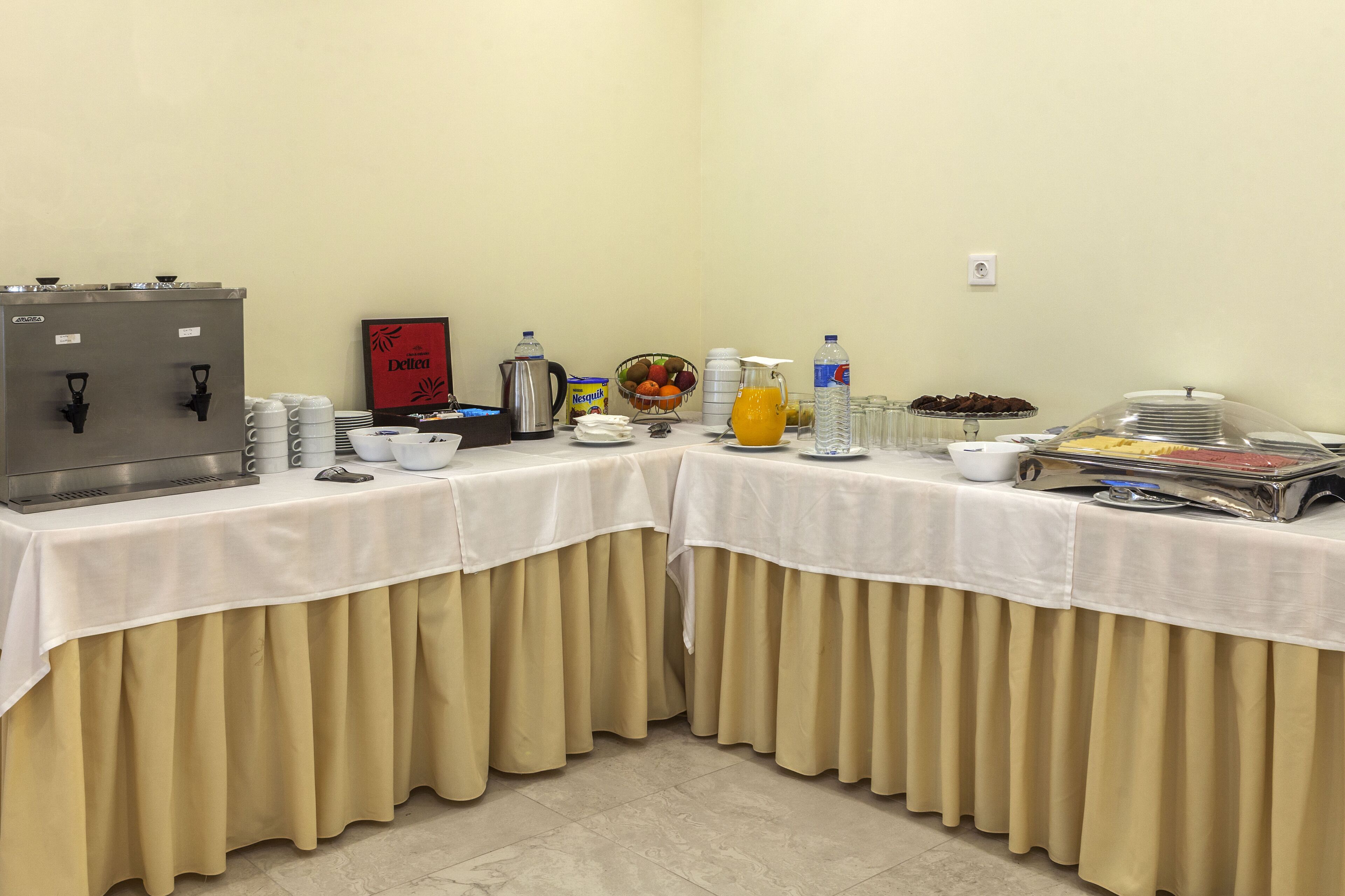 Montaje de bufé con estación de café, frutero, zumos y diversos alimentos.