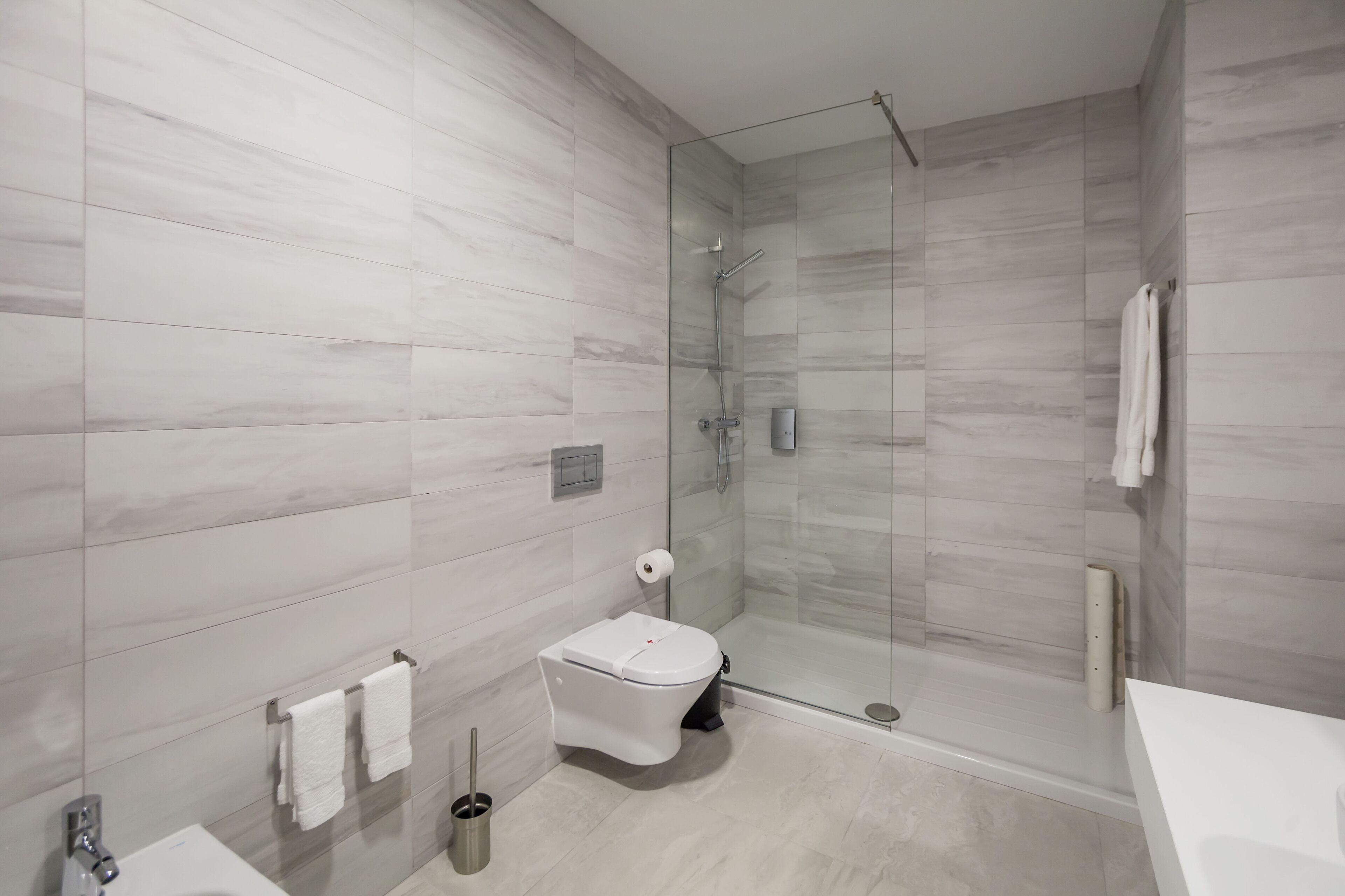 Une salle de bain moderne dotée d’une douche à parois de verre, de toilettes et d’un lavabo.