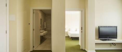 A hotel room with a bed, a television, and a bathroom visible through an open door.