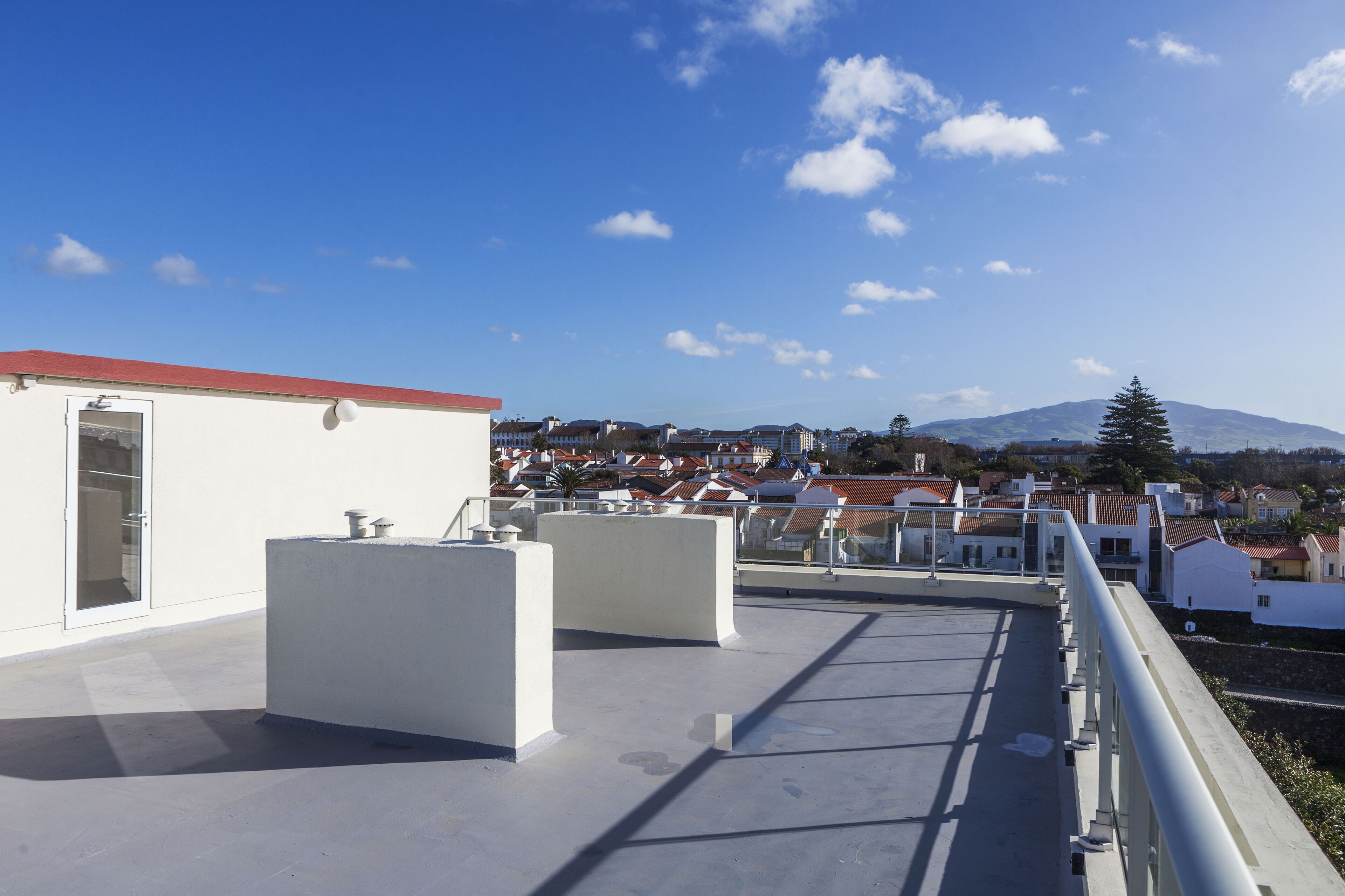 Una terraza en la azotea con vistas despejadas a una montaña y edificios residenciales al fondo.