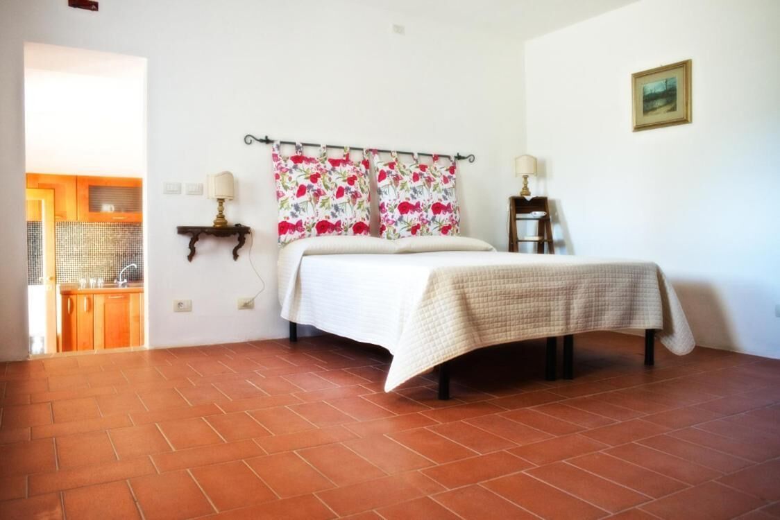 Ein Schlafzimmer mit einem Bett, zwei Nachttischlampen, einem blumigen Vorhang und einem kleinen Tisch mit Lampe.
