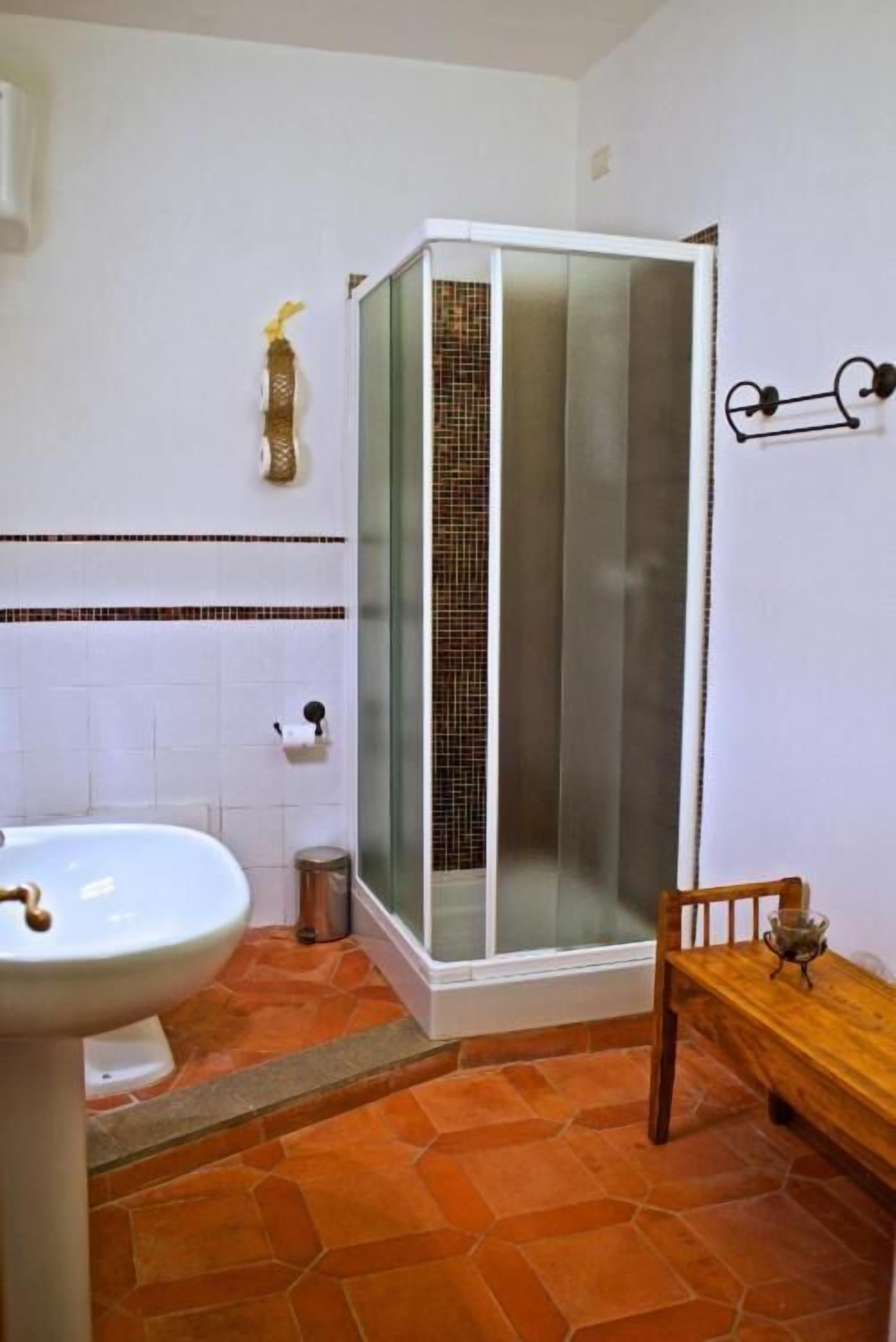 Un baño con ducha, lavabo y banco.
