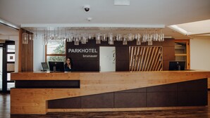 Una mesa de recepción con un cartel que dice "PARKHOTEL brünauer" y una computadora.