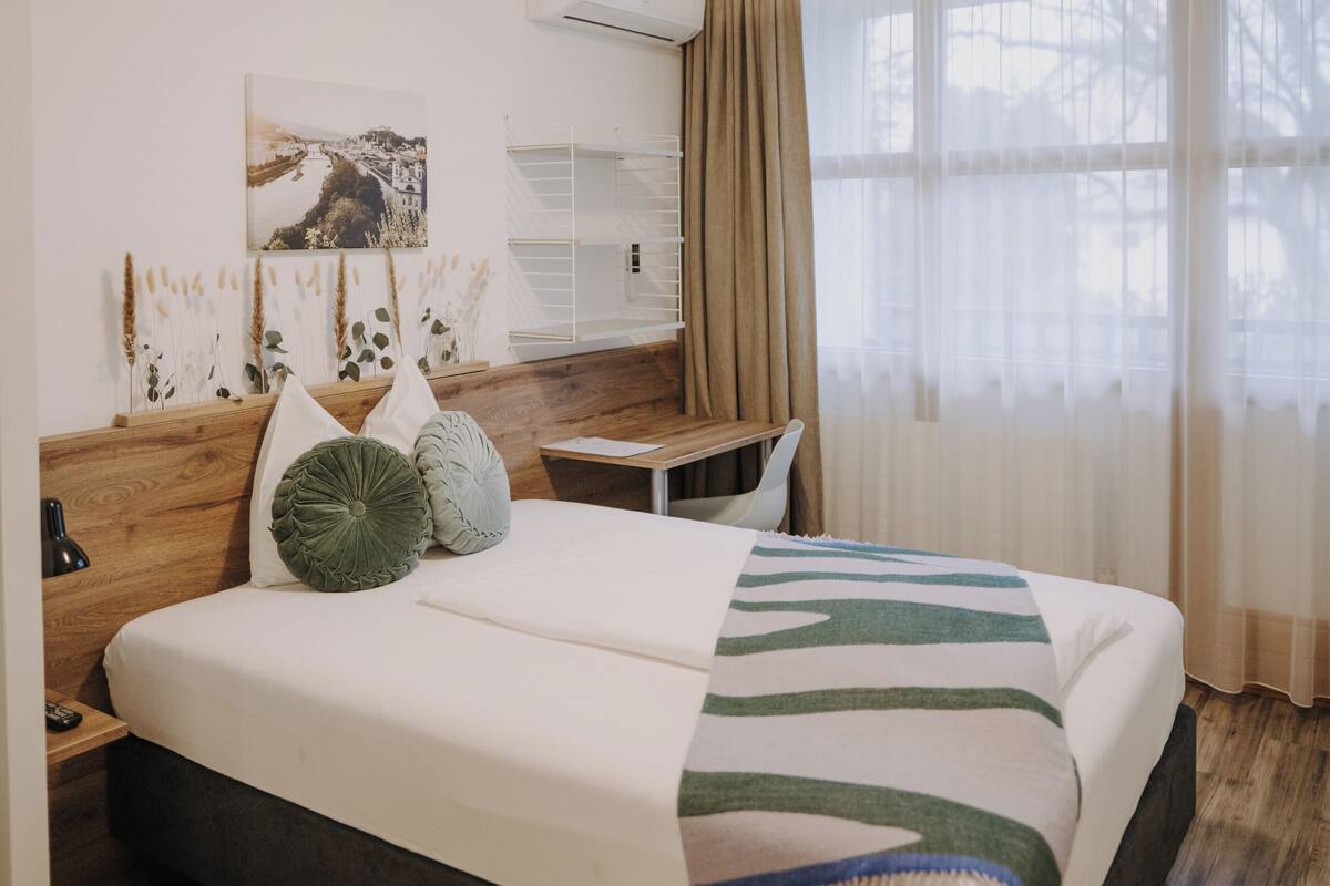Habitación de hotel con una cama grande, un escritorio y una ventana con cortinas.