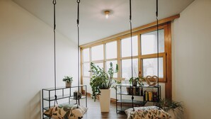 Una habitación con un ventanal grande, piso de madera y una estantería con libros y objetos decorativos.