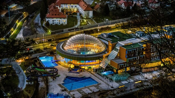 Un edificio grande y circular con una cúpula de vidrio, rodeado por una piscina y un tobogán de agua.