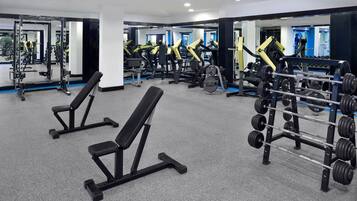 Ett gym med utrustning för styrketräning, bänkar och speglar.