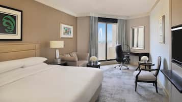 Habitación de hotel con una cama grande, un escritorio, una silla y un televisor.