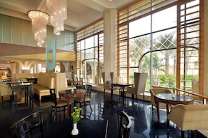 A spacious lobby with a seating area, a reception desk, and large windows offering views of palm trees. - InterContinental Jeddah by IHG (Jeddah)