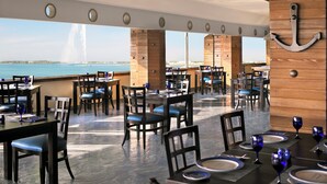 A restaurant with tables set for dining, chairs, and a view of the sea. - InterContinental Jeddah by IHG (Jeddah)