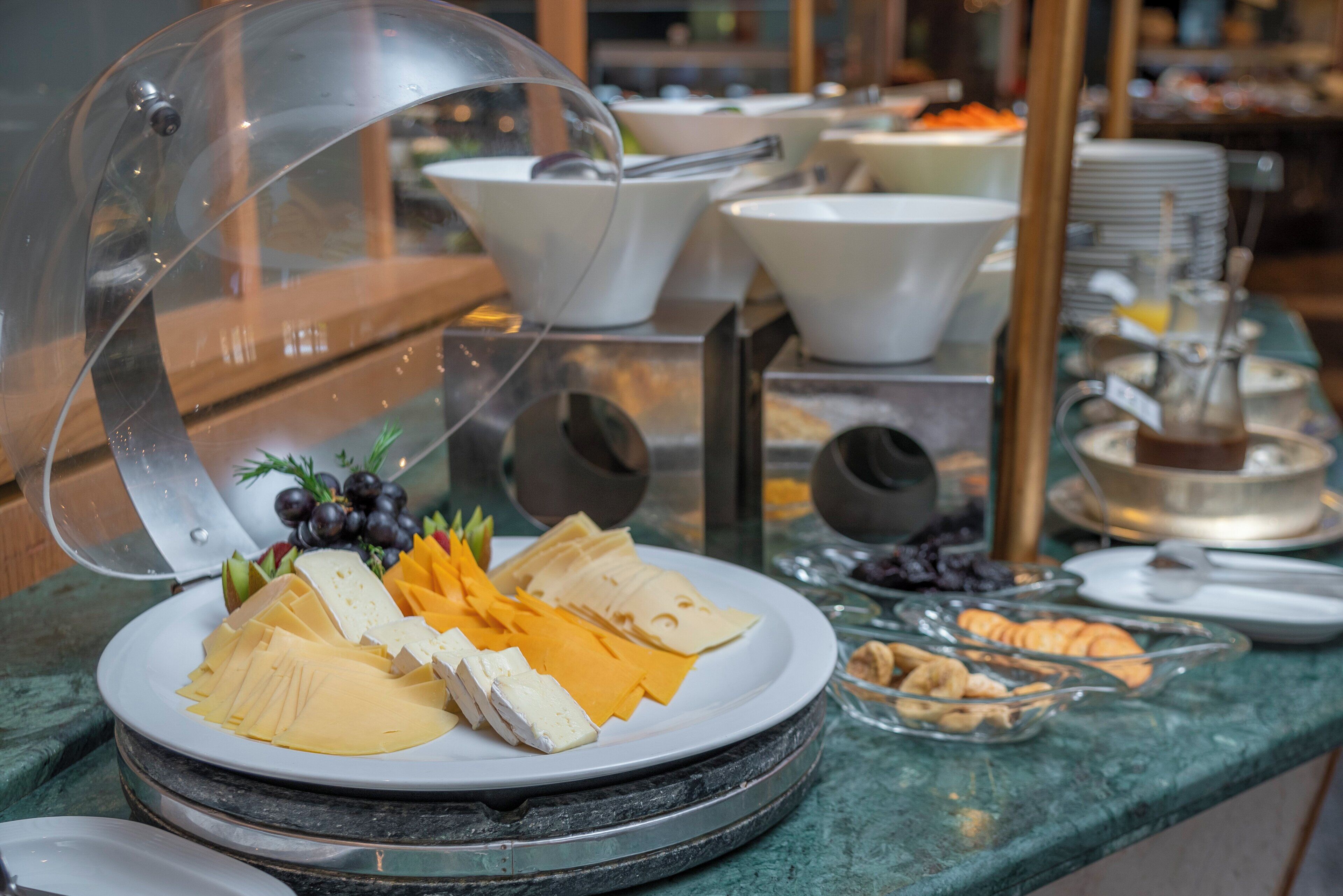 A buffet with various cheeses, fruits, and pastries.